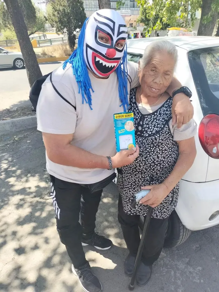Luchador enmascarado entrega un auxiliar auditivo a una mujer mayor