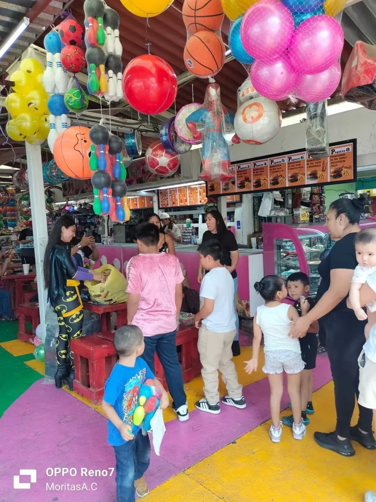 Niñas y niños reciben juguetes entre globos y balones