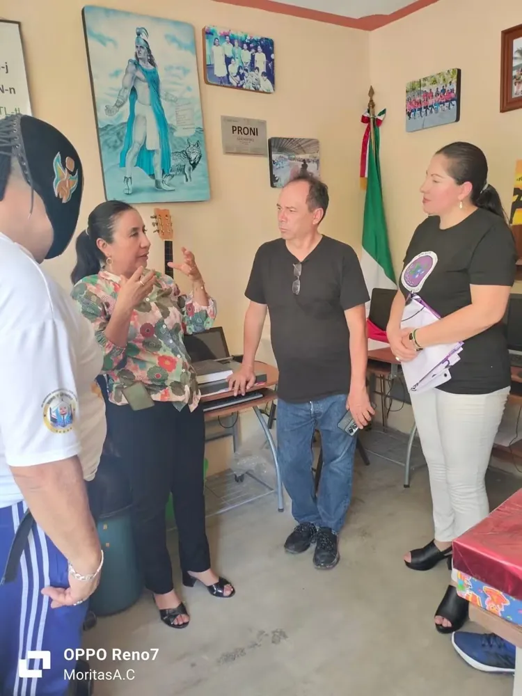 Integrantes de la fundación y un luchador conversan en una oficina escolar