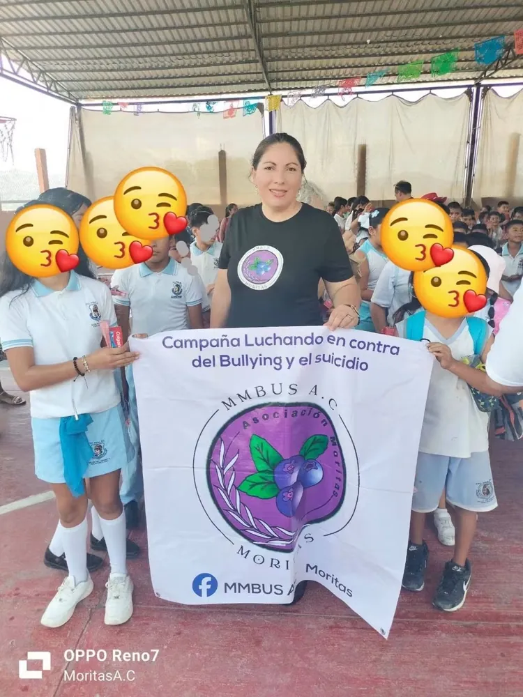 Integrante de la fundación con estudiantes y la lona de la campaña contra el bullying