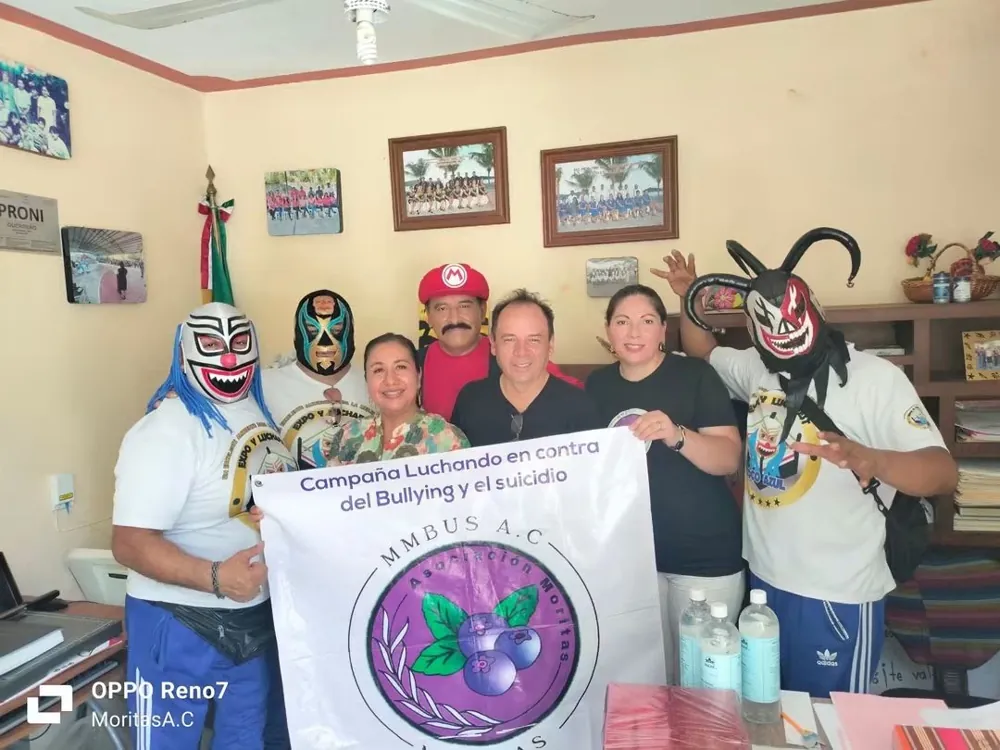 Luchadores y equipo de la fundación con la lona de la campaña contra el bullying y el suicidio