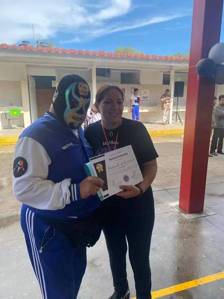 Luchador y una integrante sostienen una constancia