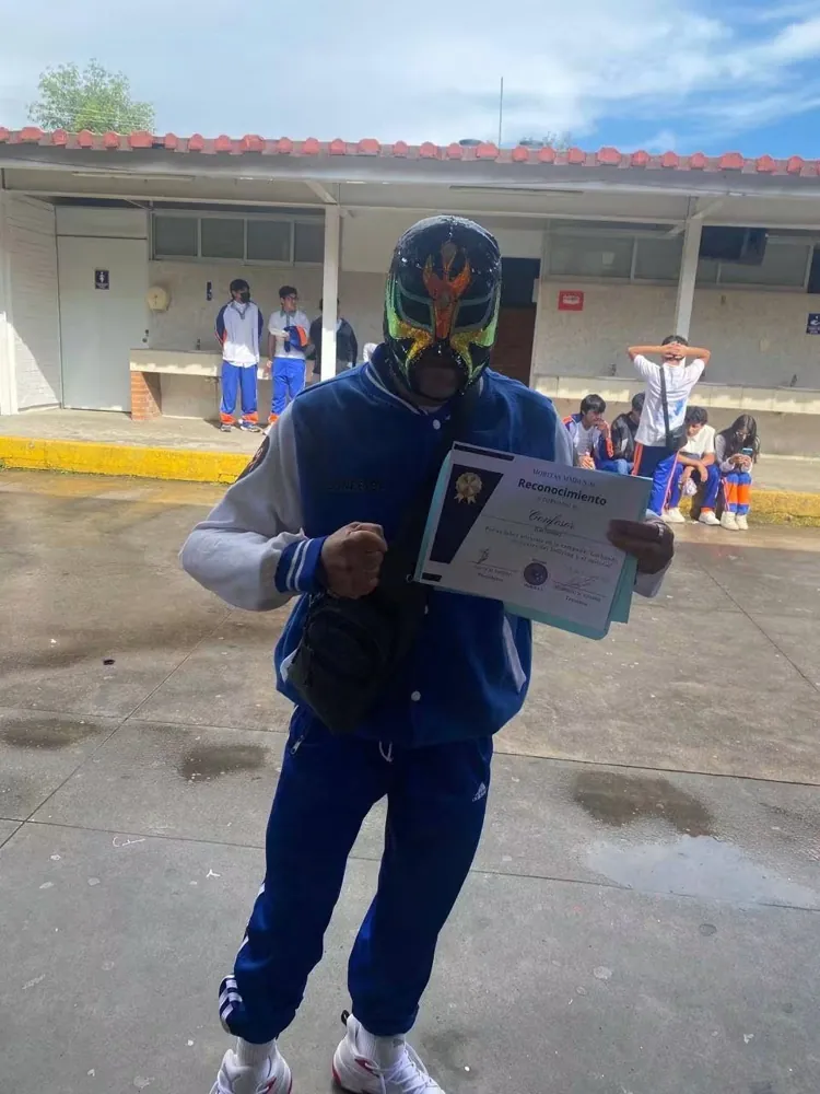 Luchador enmascarado con su constancia en la escuela